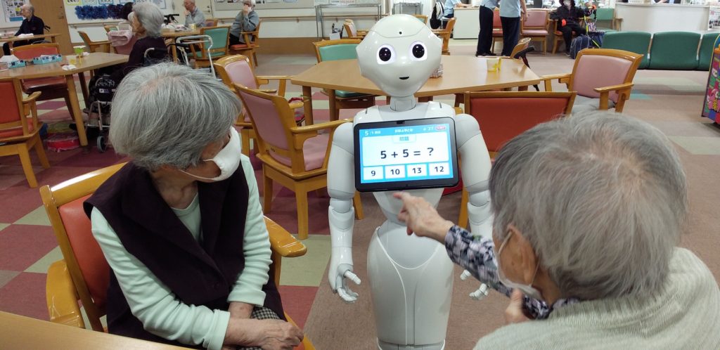 介護ロボットを使用した認知機能訓練。高齢者がロボットとの対話で脳トレーニングに参加している。